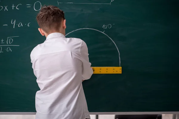 Schoolboy studying geometry in front of blackboard — Stock Photo, Image