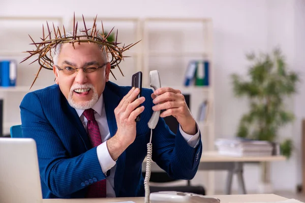 Alter männlicher Angestellter trägt stacheligen Kranz auf dem Kopf — Stockfoto