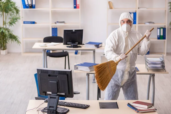 Empreiteiro velho limpando o escritório segurando vassoura — Fotografia de Stock