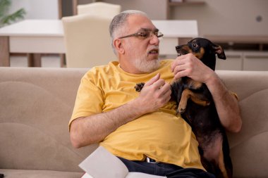 Evde köpeği olan yaşlı bir adam.