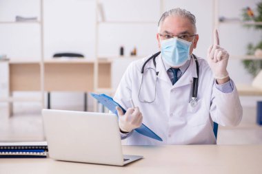 Klinikte çalışan yaşlı erkek doktor.