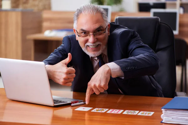 Velho empregado masculino jogando cartas no local de trabalho — Fotografia de Stock