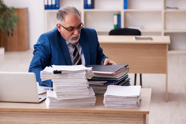 Velho empregado masculino e muito trabalho no escritório — Fotografia de Stock