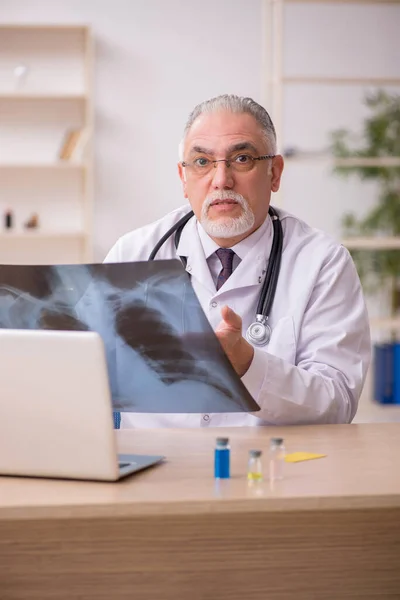 Oude mannelijke arts radioloog werkzaam in de kliniek tijdens pandemie — Stockfoto