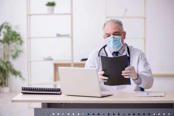 Klinikte çalışan yaşlı erkek doktor. — Stok fotoğraf