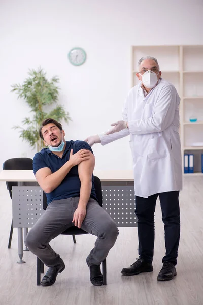 Junge männliche Patientin besucht alten Arzt im Impfpass — Stockfoto