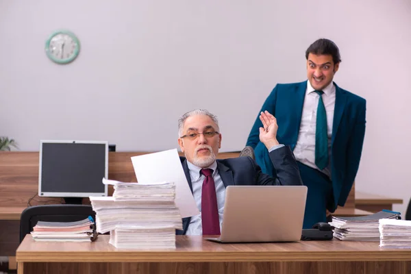 Velho empregador masculino e jovem assistente no conceito de bullying — Fotografia de Stock