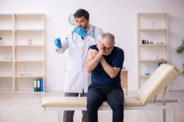 Yaşlı bir erkek hasta aşıyla genç bir doktoru ziyaret ediyor.