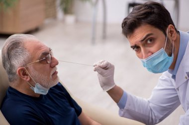 Yaşlı erkek hasta genç doktor otorhinolaryngologis 'i ziyaret ediyor.