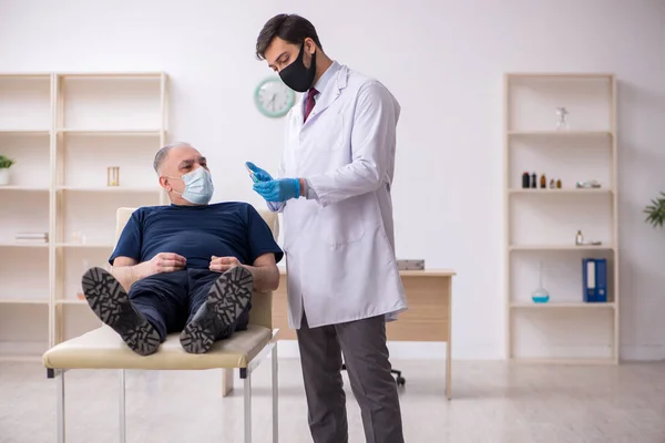 Old male patient visiting young male doctor in vaccination conce — Stock Photo, Image