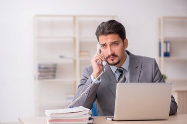 Ofisteki aşırı işten memnun olmayan genç bir erkek işçi.