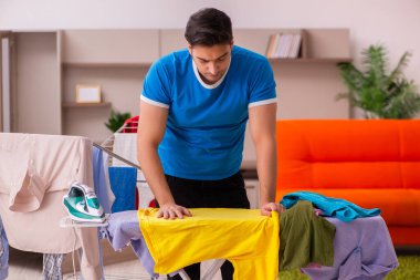 Genç adam evde ütü yapıyor.