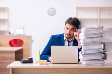 Genç bir erkek çalışan ve ofiste çok fazla iş var.