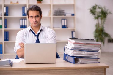 Genç bir erkek çalışan ve ofiste bir sürü iş var.