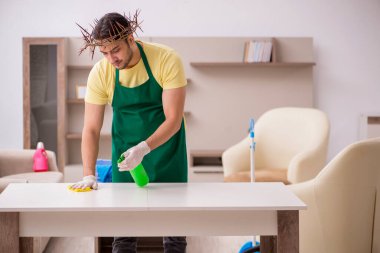 Genç erkek müteahhit, baş temizleme yerine dikenli çelenk giyiyor.