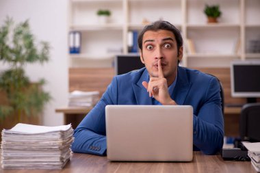 Genç bir erkek çalışan ve ofiste bir sürü iş var.