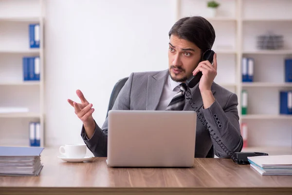 Joven empleado masculino atractivo sentado en el lugar de trabajo —  Fotos de Stock