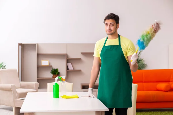 Jovem empreiteiro limpando a casa dentro de casa — Fotografia de Stock