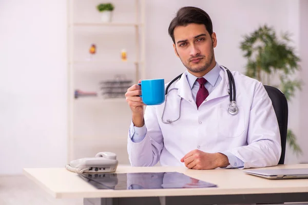 Ung manlig läkare dricker kaffe på kliniken — Stockfoto