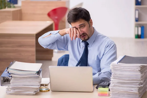 Joven empleado masculino y demasiado trabajo en la oficina — Foto de Stock