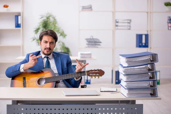 Jeune employé masculin jouant de la guitare sur le lieu de travail — Photo