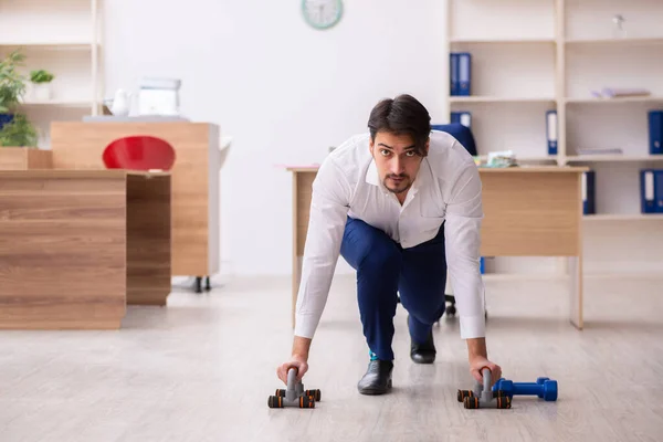 Jovem funcionário do sexo masculino fazendo exercícios esportivos durante o intervalo — Fotografia de Stock