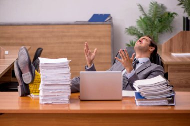 Genç bir erkek çalışan ve ofiste çok fazla iş var.