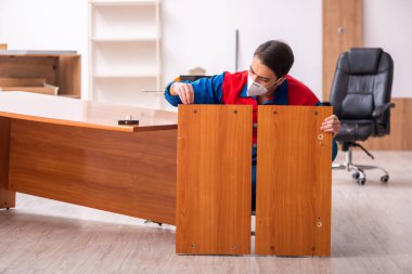 Genç erkek marangoz salgın sırasında ofiste çalışıyor.