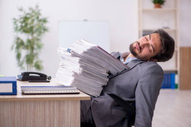 Genç bir erkek çalışan ve ofiste çok fazla iş var.