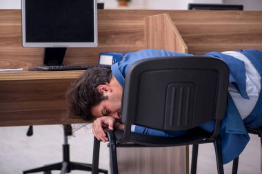 Genç erkek çalışan işyerinde oturuyor.
