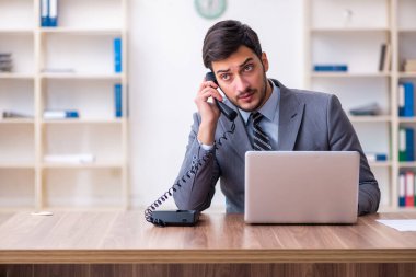 Genç yakışıklı işadamı ofiste çalışıyor.