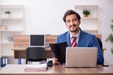 Genç erkek çalışan işyerinde oturuyor.