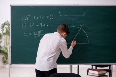 Okul çocuğu tahtanın önünde geometri okuyor.