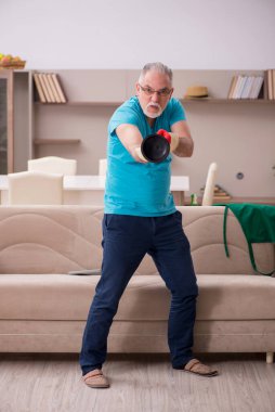 Yaşlı adam evde su tesisatı yapıyor.