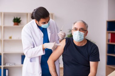 Yaşlı adam covid-19 aşı konseptinde genç doktoru ziyaret ediyor.
