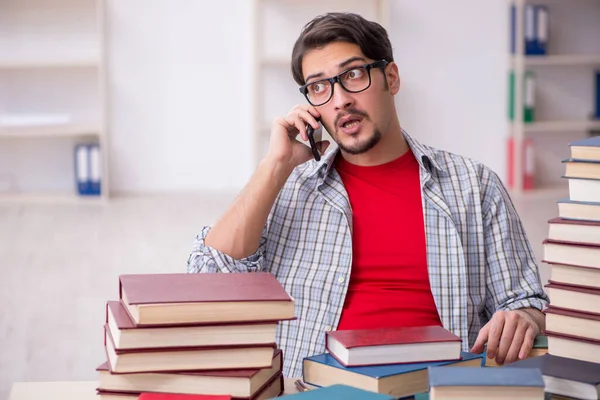 Joven estudiante masculino y demasiados libros en el aula — Foto de Stock