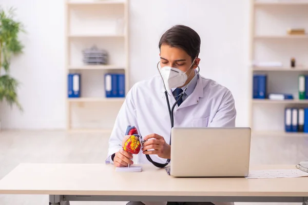 Genç erkek doktor kardiyolog pand sırasında klinikte çalışıyor. — Stok fotoğraf