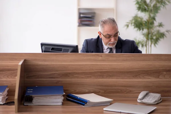 Hombre anciano empleado sentado en el lugar de trabajo — Foto de Stock