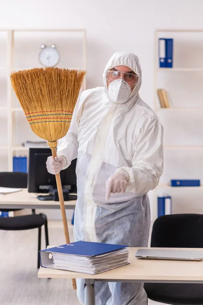 Παλιός εργολήπτης καθαρίζει το γραφείο κρατώντας σκούπα — Φωτογραφία Αρχείου