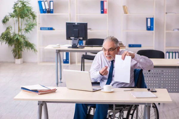 Vecchio dipendente di sesso maschile in sedia a rotelle seduto in ufficio — Foto Stock