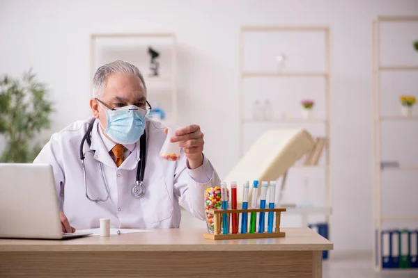 Yaşlı erkek doktor salgın sırasında klinikte çalışıyor. — Stok fotoğraf