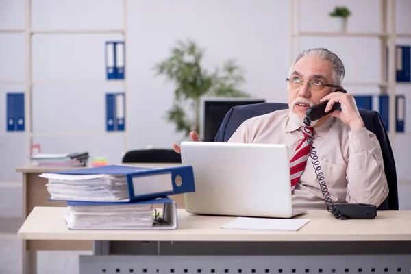 Starý muž zaměstnanec sedí na pracovišti — Stock fotografie
