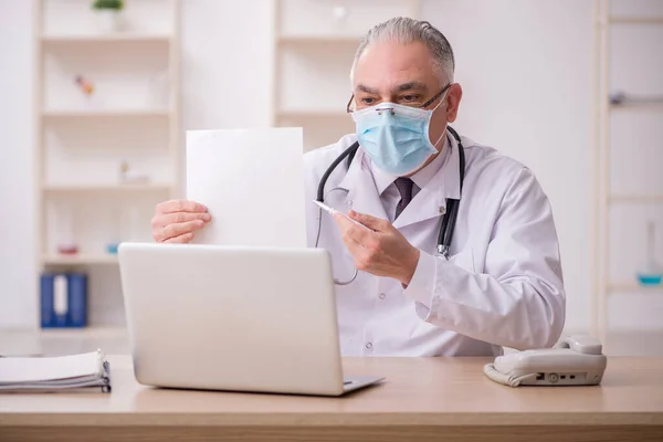 Vieux médecin masculin travaillant à la clinique pendant la pandémie — Photo