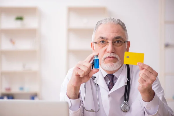 Kredi kartı ödemesi ve aşı konseptinde yaşlı bir erkek doktor. — Stok fotoğraf