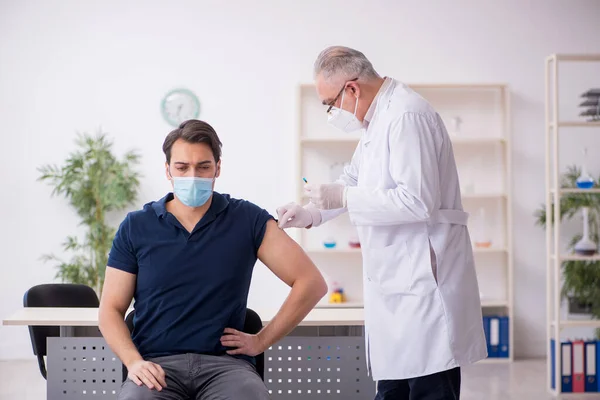 Junge männliche Patientin besucht alten Arzt im Impfpass — Stockfoto