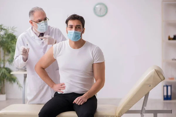 Junge männliche Patientin besucht alten Arzt im Impfpass — Stockfoto