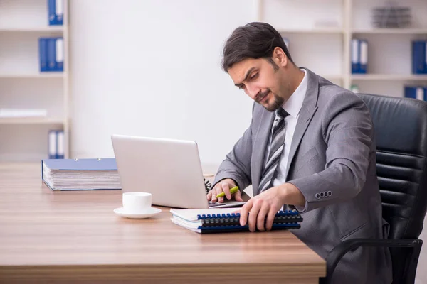 Jovem atraente masculino empregado sentado no local de trabalho — Fotografia de Stock