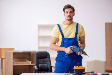 Genç erkek marangoz ofiste çalışıyor.