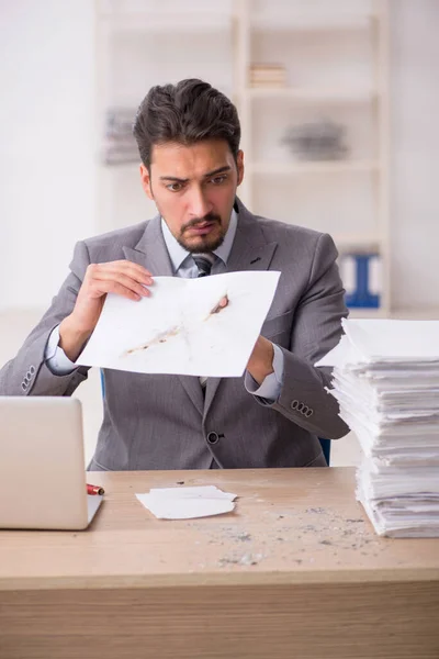 Jonge mannelijke werknemer ongelukkig met overmatig werk in het kantoor — Stockfoto