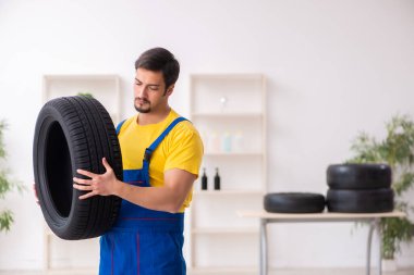 Atölyede lastiği olan genç bir erkek tamirci.